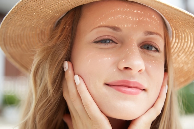 Closeup shot de jeune femme caucasienne dans un chapeau de paille toucher doucement son visage