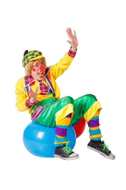 Le Clown Drôle S'assied Sur La Boule Bleue D'isolement Sur Le Fond Blanc Photo Premium