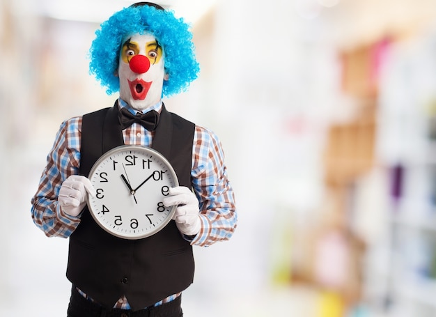 Clown avec le visage drôle tenant une horloge