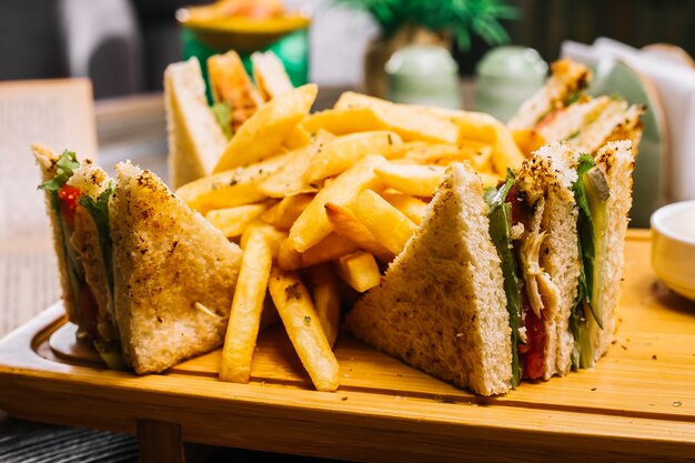 Club sandwich pain grillé poulet tomate concombre frites mayonnaise ketchup vue latérale