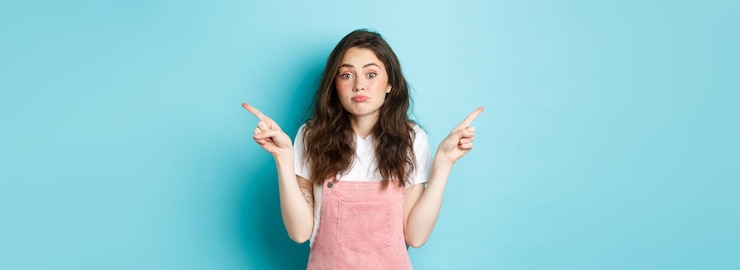 Photo gratuit clueless et confus jolie fille timide haussant les doigts pointant les doigts sur le côté à deux côtés avec