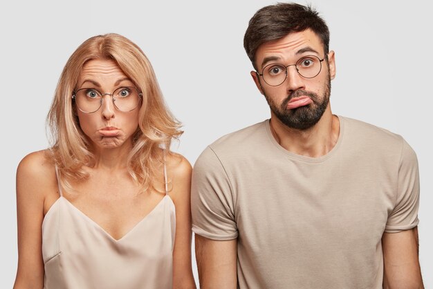 Clueless douteux couple de famille haussent les épaules dans la confusion, les lèvres de la bourse, ne sais pas où passer des vacances