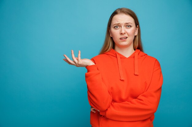 Clueless jeune femme blonde montrant la main vide