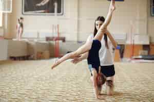 Photo gratuite coach avec étudiant. gymnastes de filles, effectue divers exercices de gymnastique et de saut. l'enfant et le sport, un mode de vie sain.