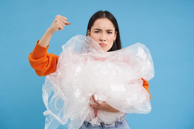 Écoactiviste en colère tenant des déchets plastiques levant le poing et luttant pour l'environnement triant les ordures re