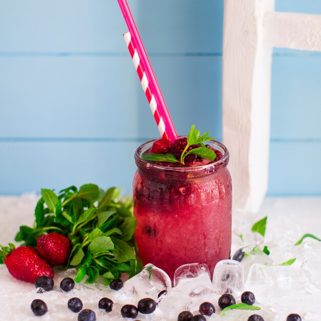 Cocktail de baies avec fraises, framboises et glaçons dans un bocal en verre