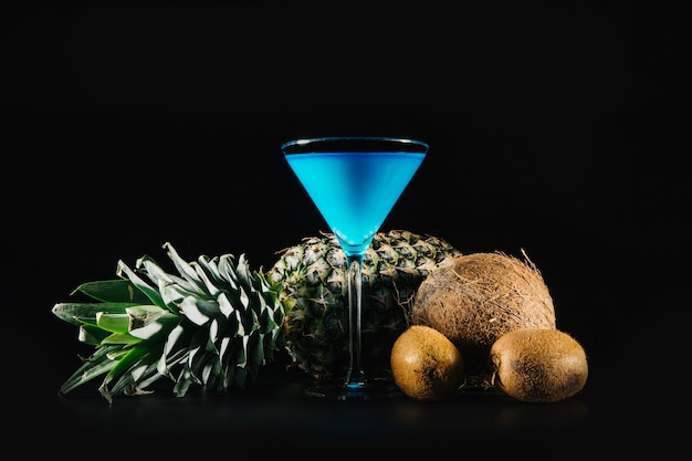 Photo gratuite cocktail bleu et fruits exotiques sur fond noir