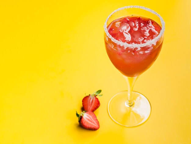 Cocktail de fraises avec des glaçons dans un verre à bord sucré