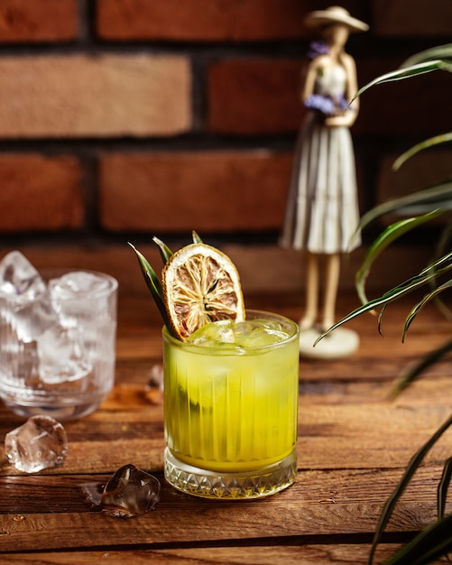 Photo gratuite un cocktail de fruits vue de face avec des glaçons sur le cocktail de bureau en bois brun jus de fruits de boisson