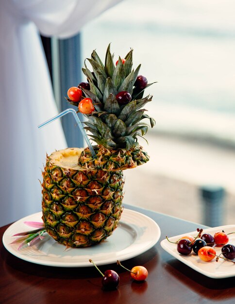 Cocktail de jus d'ananas avec fruits et baies à l'intérieur du cône.