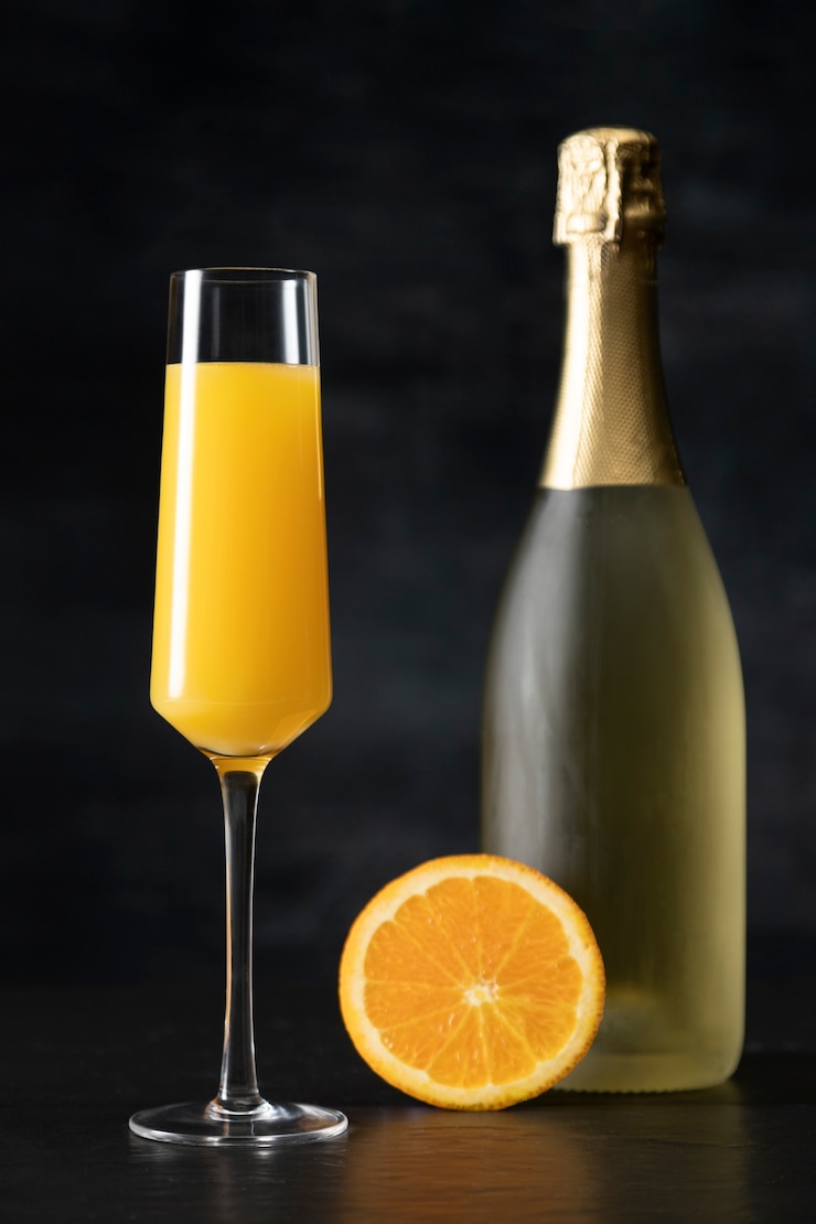Photo gratuit cocktail mimosa avec bouteille et tranche d'orange
