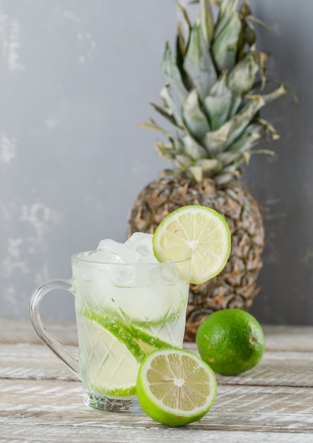 Cocktail mojito glacé aux limes, ananas dans une tasse en bois et plâtre, vue latérale.