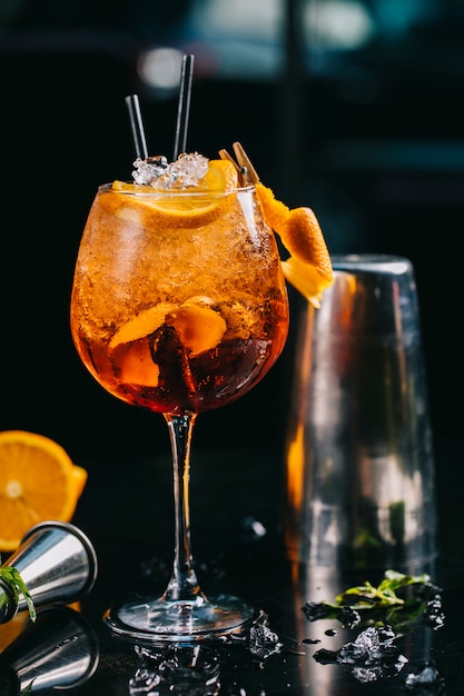 Cocktail orange dans un verre avec des glaçons et des pipes émincés.