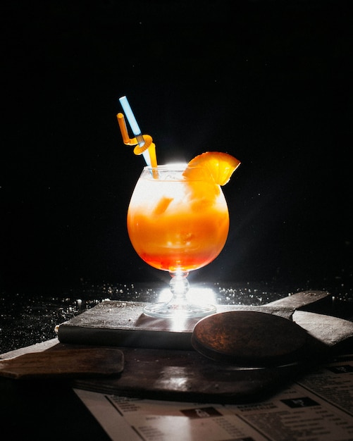 Photo gratuite cocktail d'orange avec de la glace et des pailles de jus d'orange frais sur le livre