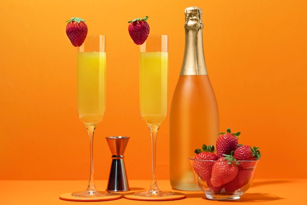 Photo gratuite cocktail savoureux de mimosa avec le fond orange