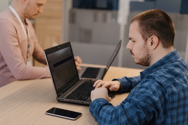 Les codeurs informatiques travaillant sur l'ordinateur portable dans le bureau debout à la table