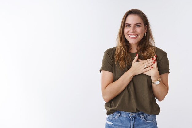 Le cœur bat l'amour fou dans l'air. Portrait insouciant charmant sympathique à la happy caucasian woman appuyez sur la poitrine des paumes vérifier heartbit avouant de la sympathie, souriant ravi fond blanc