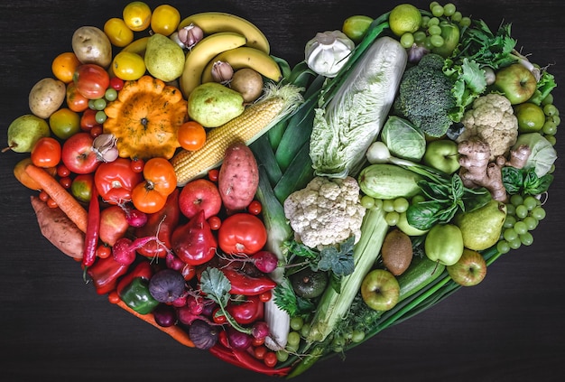 Photo gratuite coeur composé de légumes frais et de fruits sur fond de bois