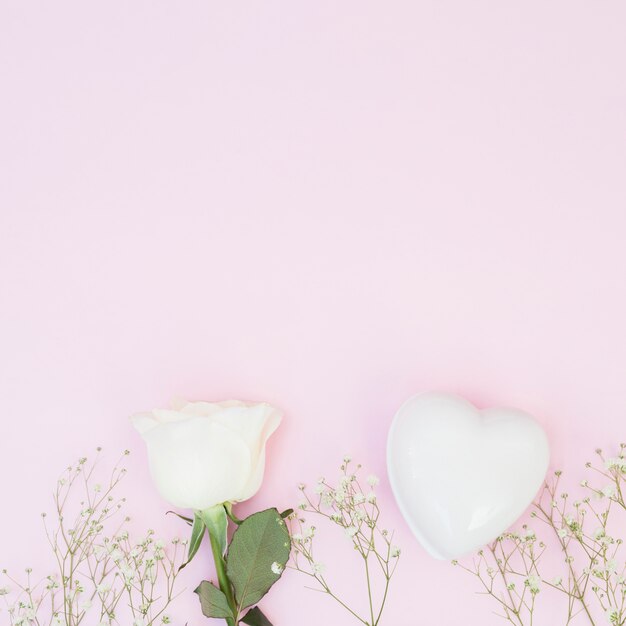 Coeur décoratif blanc près des plantes et rose