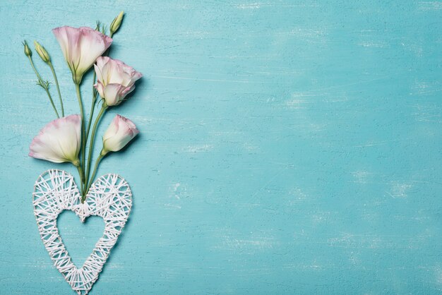 Coeur décoratif fait main avec des fleurs d&#39;eustoma sur un fond bleu texturé