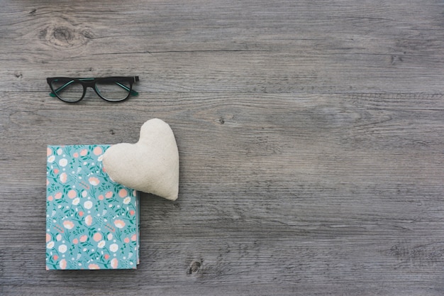 Coeur, livre et lunettes sur la surface en bois