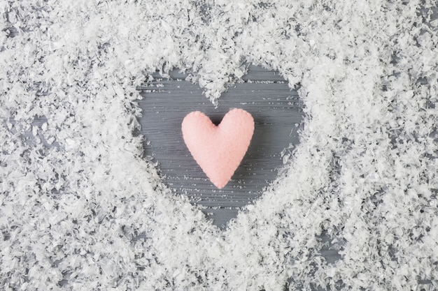 Photo gratuite coeur rose entre neige décorative sur bureau en bois