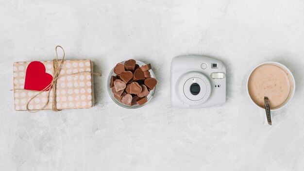 Coeurs en chocolat, boîte à cadeaux, appareil photo et tasse de boisson