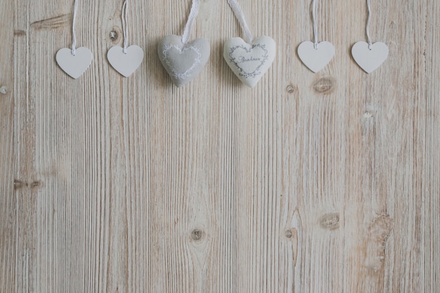 Photo gratuite coeurs gris et blanc suspendus sur des cordes sur une surface en bois