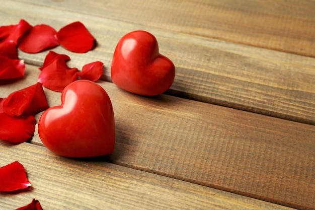 Coeurs rouges avec des pétales de fleurs sur fond de bois