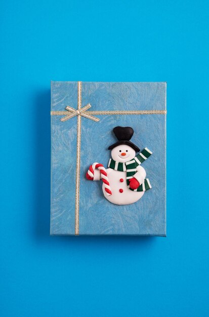 Coffret cadeau de Noël bleu décoré d'un bonhomme de neige dans le fond bleu