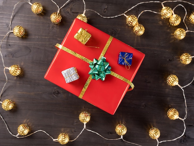 Coffret cadeau de Noël sur fond en bois avec petits cadeaux et lumière de Noël. Bonnes vacances d'hiver.