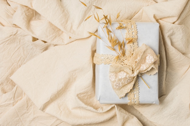 Coffret cadeau noué avec de la dentelle de créateur sur un drap froissé