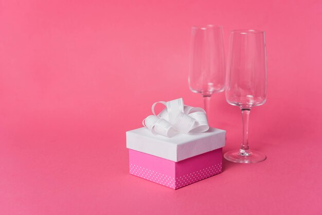 Coffret avec un verre de champagne vide lunettes sur fond rose