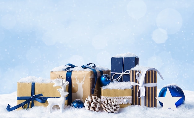 Coffrets cadeaux de noël avec des boules bleues, des boules et des cerfs blancs recouverts de neige. fond de paysage bleu clair de noël d'hiver avec espace de copie.