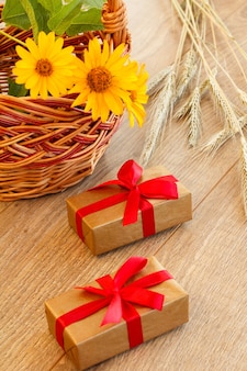 Coffrets cadeaux, panier en osier avec fleurs et épillets de blé sur planches de bois. vue de dessus.