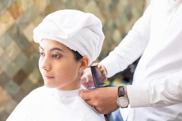 Le coiffeur attache le cap sur une femme féminine sérieuse