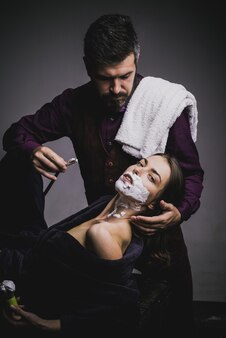Coiffeur et barbier femme et homme jouant à des jeux de domination idées de lame de rasoir sur le salon de coiffure et ...