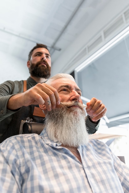 Coiffeur coiffant moustache au client dans le salon