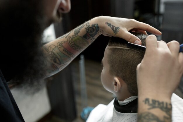 Coiffeur coupe les cheveux du petit garçon