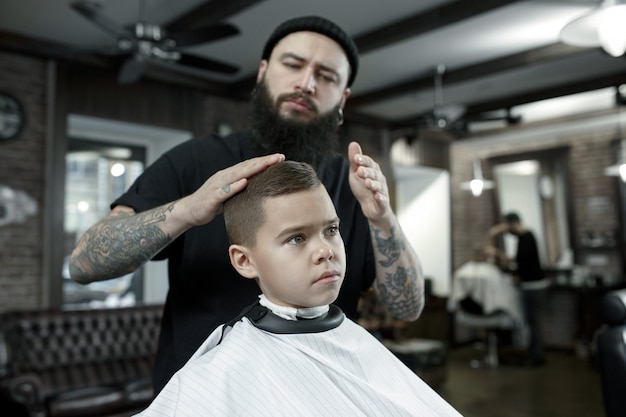 Coiffeur coupe les cheveux du petit garçon