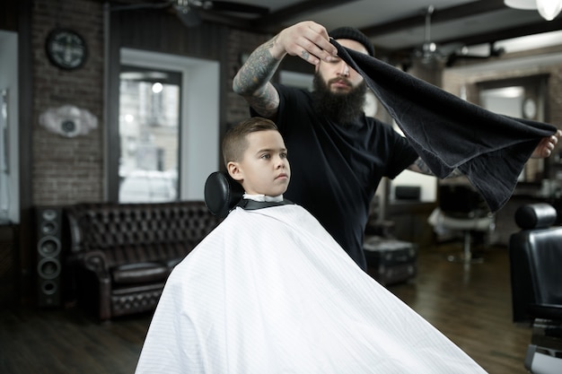 Coiffeur coupe les cheveux du petit garçon