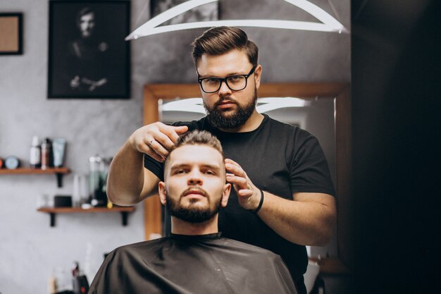 Coiffeur dans un salon de coiffure coiffant les cheveux d'un client