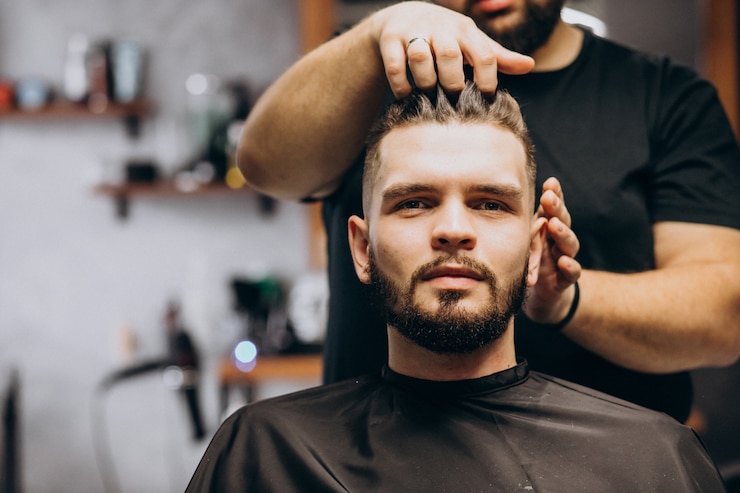 Photo gratuit coiffeur dans un salon de coiffure coiffant les cheveux d'un client