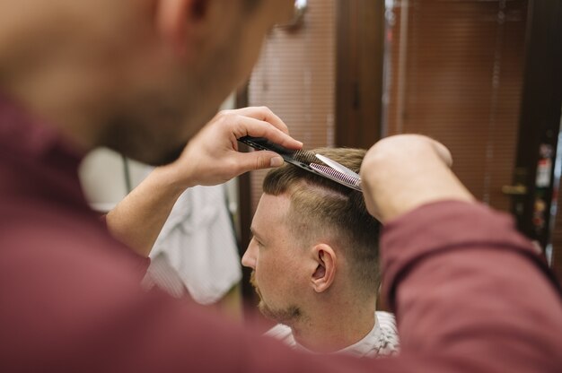 Coiffeur donnant une coupe de cheveux à un client