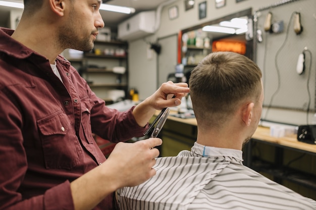 Coiffeur donnant une coupe de cheveux à un client