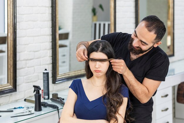 Coiffeur drôle tenant les cheveux du client sur son visage Photo de haute qualité