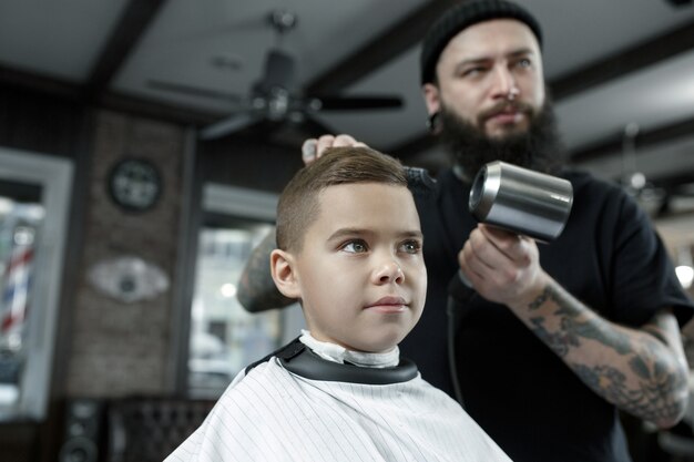 Coiffeur enfants coupe petit garçon sur un fond sombre.