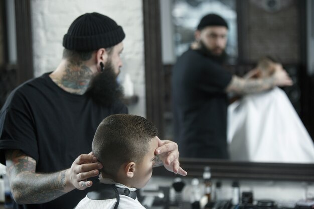 Coiffeur enfants coupe petit garçon sur un fond sombre.