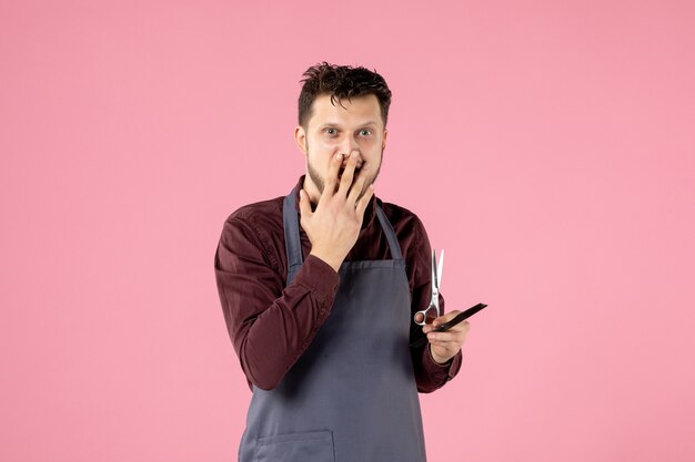 coiffeur homme vue de face avec brosse à cheveux et ciseaux sur fond rose