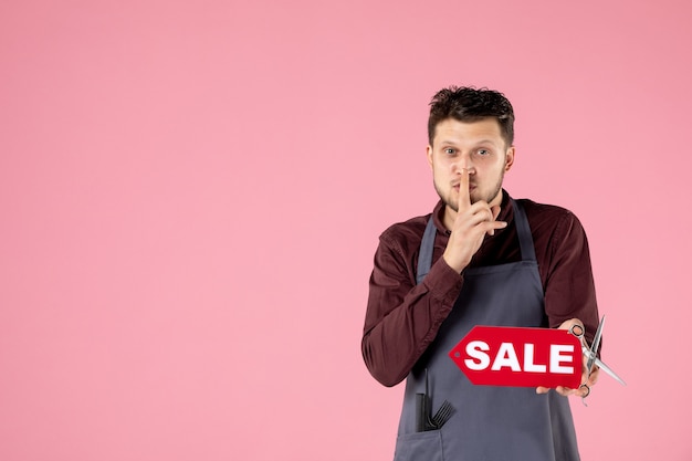 coiffeur homme vue de face avec plaque signalétique de vente et ciseaux sur fond rose